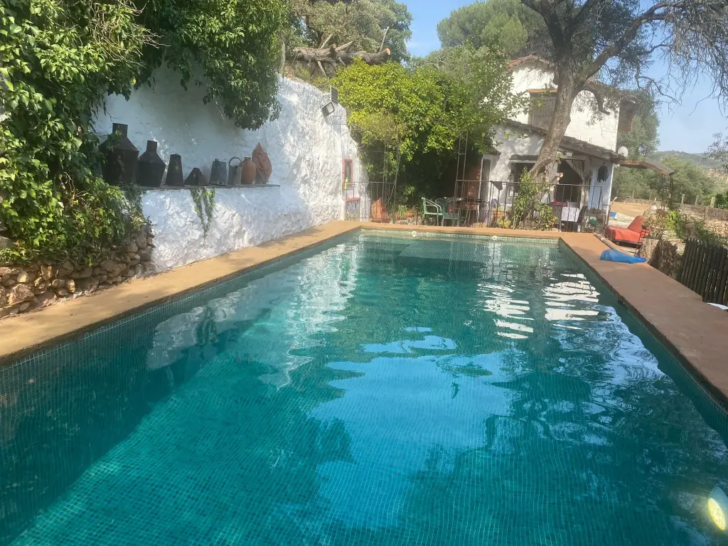 Piscina privada de la casa rural La Toscana con la fachada encalada al fondo, Linares de la Sierra