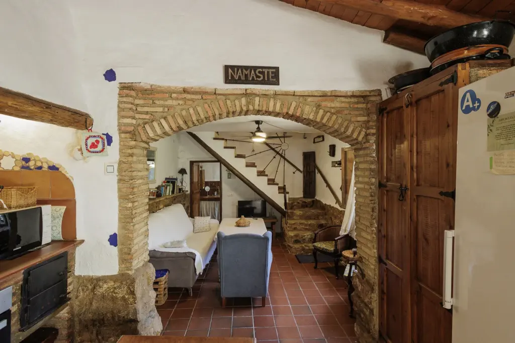Salón con arco de ladrillo visto, sofás y escalera de la casa rural La Toscana