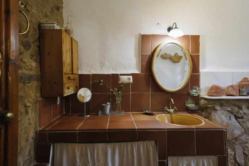 Baño con lavabo de azulejos terracota y espejo oval