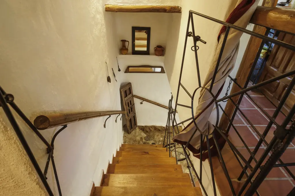 Escalera de madera con barandilla de forja hacia los dormitorios