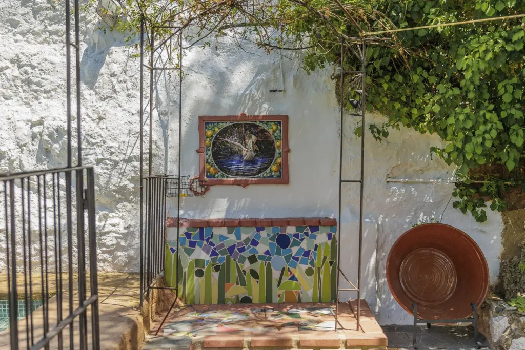 Patio encalado con fuente de mosaico y cancela de hierro