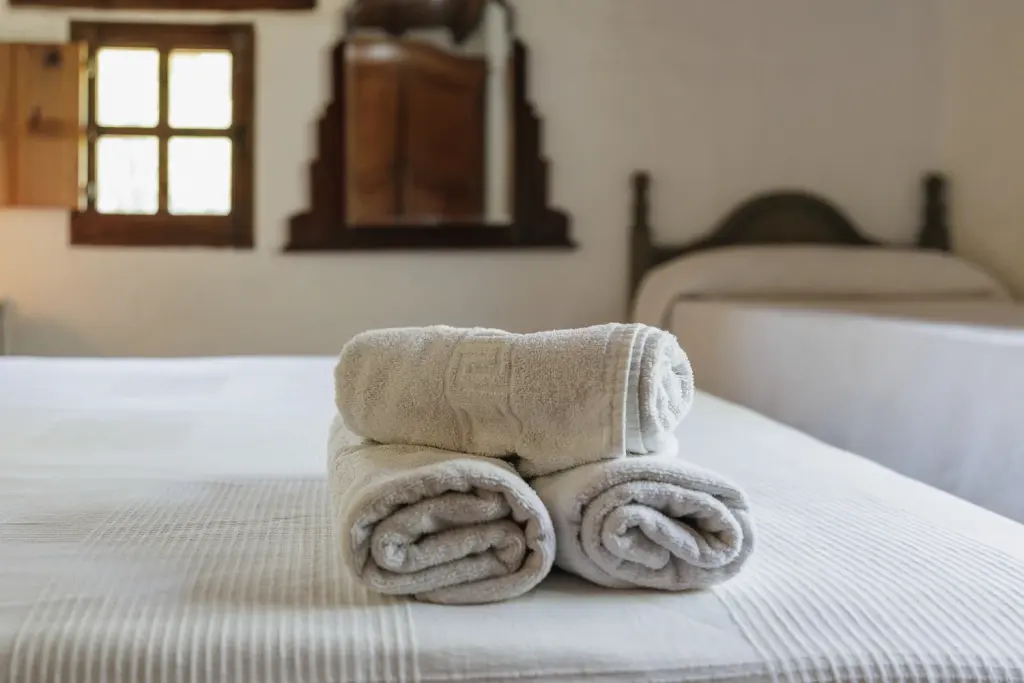 Toallas sobre la cama de un dormitorio con ventana de madera