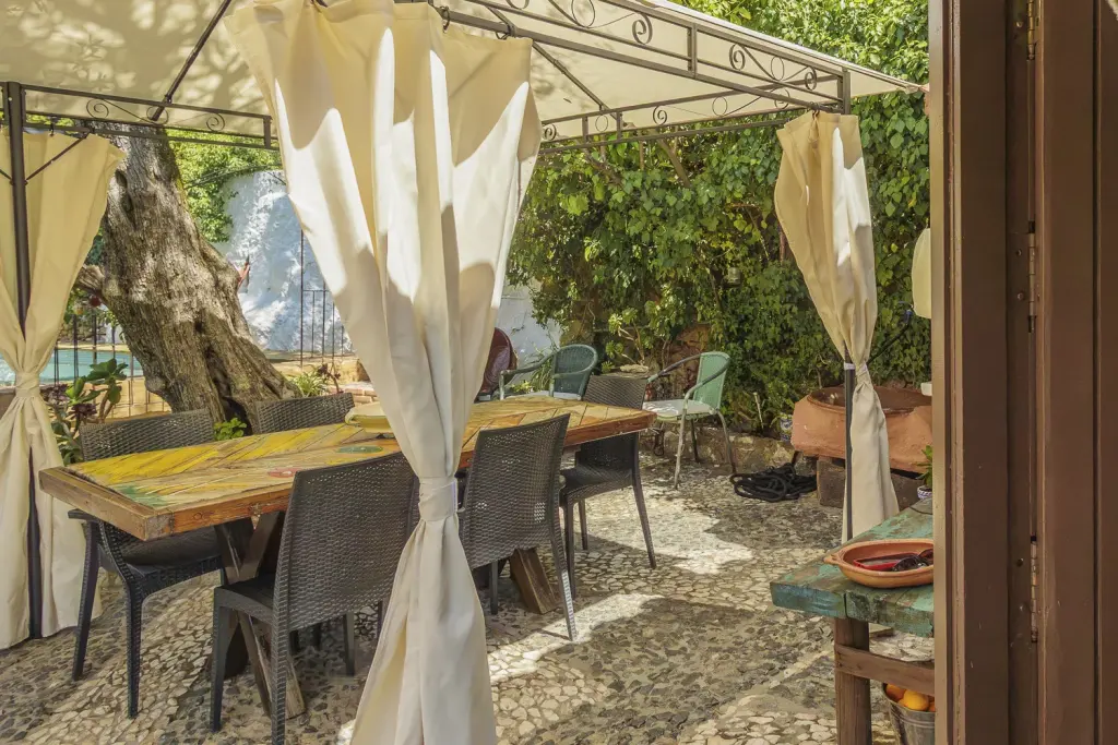 Mesa de comedor bajo el cenador de cortinas para comer al aire libre